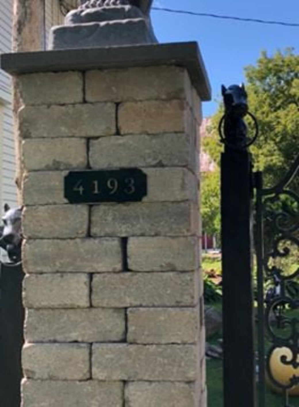 Personalized metal address plaque on brick.